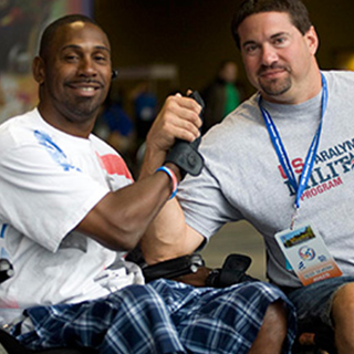 two veterans in wheelchairs grasping hands