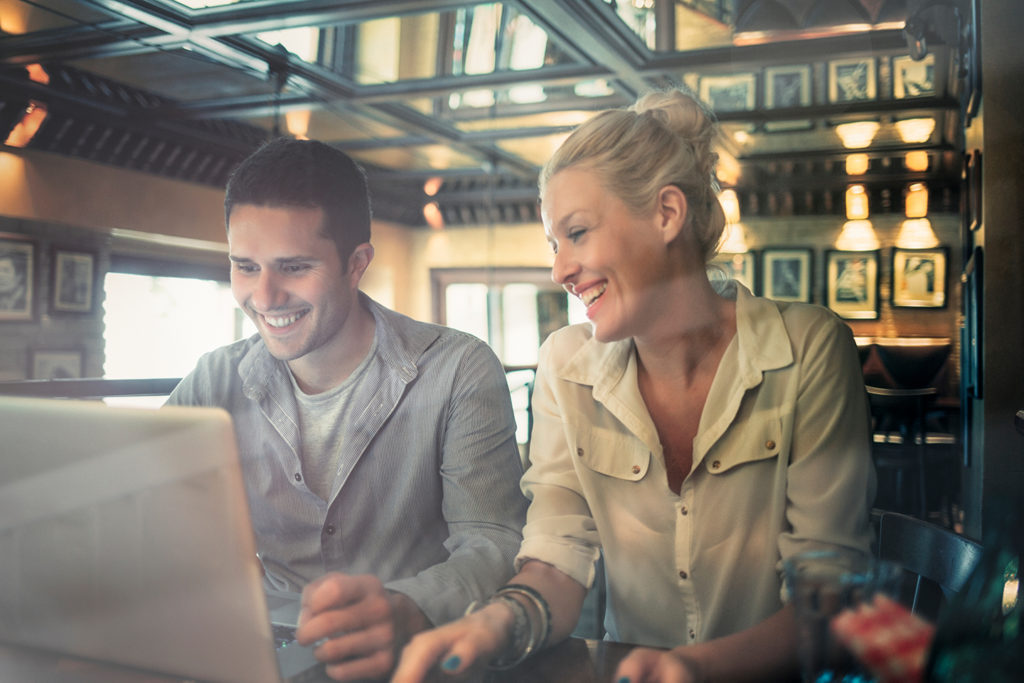 two people in a cafe on a laptop