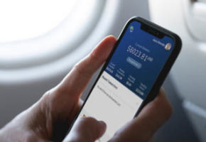 Phone displaying Allied Wallet eWallet app in front of airplane window