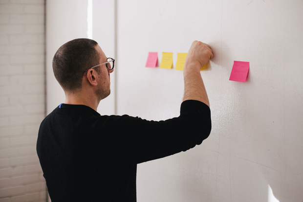 man putting post-it notes on whiteboard